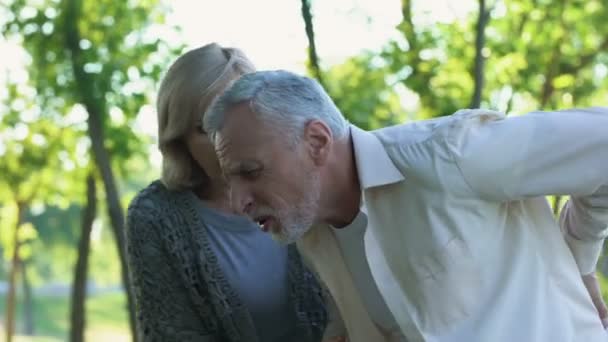 成熟的人感觉尖锐背部疼痛 而步行在公园照顾妻子帮助他 — 图库视频影像