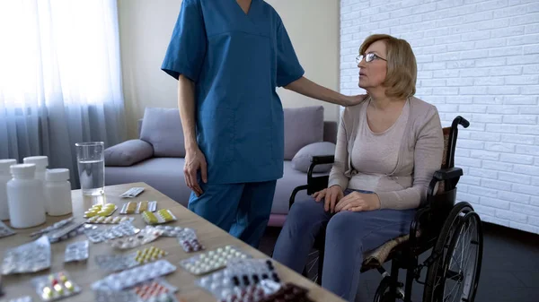 Nurse Comforting Tired Female Patient Wheelchair Nursing Home Treatment — Stockfoto