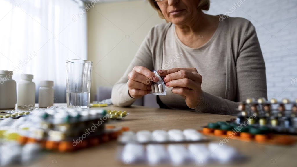 Unhealthy elderly lady drinking pills, vitamins, illness symptoms, hypochondria