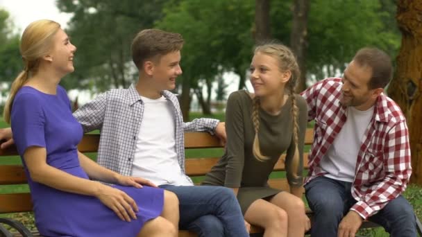 身近な人たちと誠実なコミュニケーション 公園のベンチに座っている幸せな家族 — ストック動画