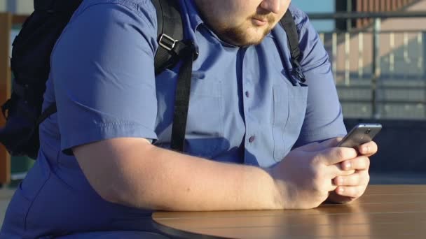 Sobrepeso Estudiante Masculino Desplazándose Teléfono Inteligente Solo Cafetería Calle Primer — Vídeo de stock