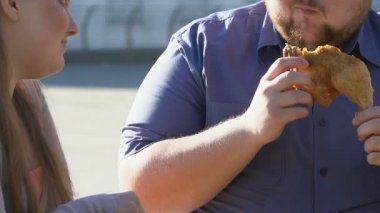 Tombul kadın obez sevgilisi yağlı kızarmış tavuk ısırma sırasında salata yemek