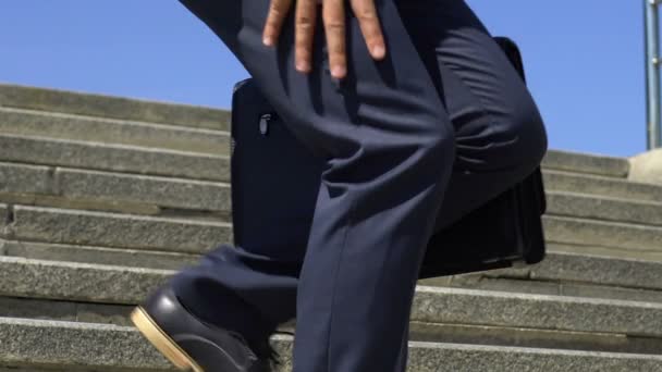 男性ビジネスマンが 膝の痛みを感じて歩く階下 関節損傷 クローズ アップ — ストック動画