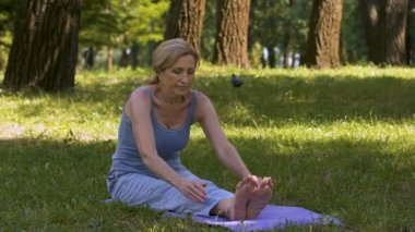 Genç Bayan mat, yoga asana Amatör, iyi durumda uyuşuk Park'ta germe