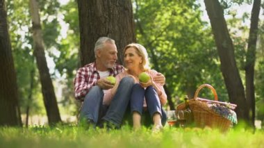 Aile hafta sonu, emekli parkta oturan çift ve yeşil elma, yemek piknik