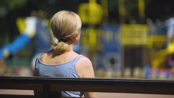 Triste Velha Fêmea Sentada Banco Playground Olhando Para Crianças Infertilidade — Vídeo de Stock