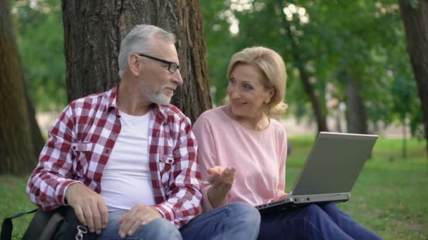 Gelukkige Paar Zittend Gras Het Kiezen Van Nieuwe Goederen Laptop — Stockvideo