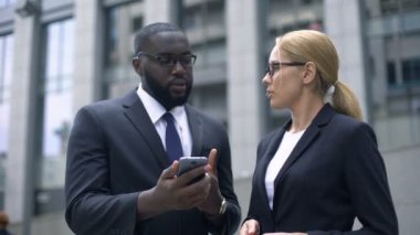 İş adamları iş arkadaşları smartphone açık havada üzerinden online iş sorunları tartışıyor