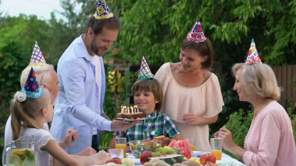 フレンドリーな家族祝い男の子誕生日キャンドル ケーキを与えるに — ストック動画