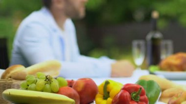 Taze meyve ve sebze tablo, mutlu erkek ve Bayan arka plan üzerinde konuşuyor