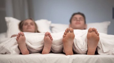 Genç çift yatakta, sağlıklı ayaklar, mantar önleyici sprey etkisi görünümünü uyku
