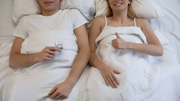 男人拿着避孕套和女朋友竖起大拇指 负责任的态度 — 图库照片