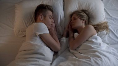 Genç çift yatakta rahat yatak ve çarşaflar, huzurlu gece rüya