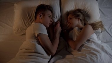 Genç adam yatakta, ilişkiler onun güzel kız arkadaşı şefkatle bakarak