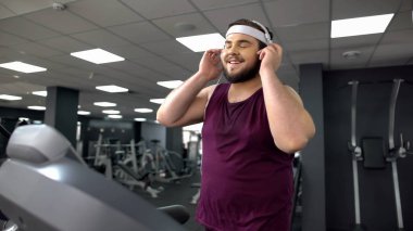 Kulaklıktaki koyarak ve koşu bandı üzerinde koşu sırasında müzik şişman adam