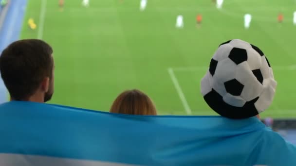 球迷们被阿根廷国旗的跳以及在体育场观看足球包裹 — 图库视频影像