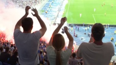 Futbol taraftarları tribünde takımın desteklenmesi için alkış, fişekleri arka plan üzerinde ateş.