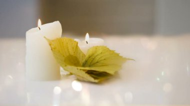 Dekor parlak beyaz arka plan üzerinde rahat ev yaprakları yanan mum ve sarı