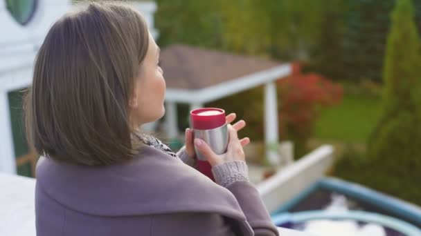 一杯のコーヒーで物思いにふける女性バルコニーの上に立って 寒い秋の日でウォーム アップ — ストック動画