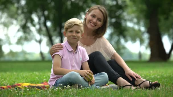 男孩抱着苹果 和妈妈坐在公园里 健康营养的概念 — 图库视频影像