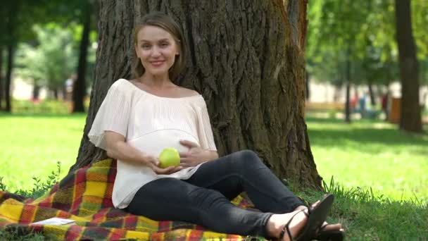 在公园展示苹果的孕妇 健康饮食的概念和生活方式 — 图库视频影像