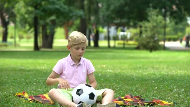 悲しい少年の孤独な公園で座っている両親をサポートおよび応援へ彼のギフトを与える — ストック動画