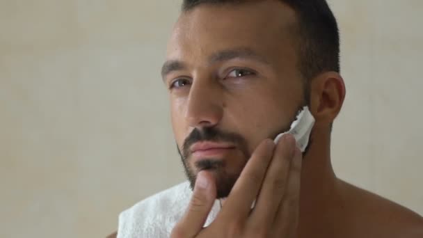 新しいスタイルのバスルームの鏡の前でシェービング クリームを適用する髭の男 — ストック動画