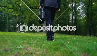 Evrak Çantası'nı çimenlerin üzerinde bırakarak ve yeşil orman, stres kaçış yürüyen adam