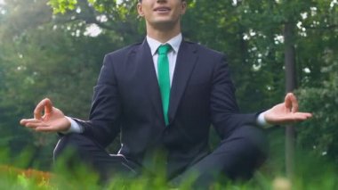 Lotus pozisyonu çim, zihin özgürlüğü üzerinde oturan iş elbiseli Genç adam