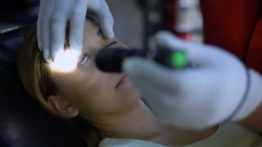 Doktor hasta gözlerinin içine, testleri gözbebeği refleksleri, baygın kurban ışık parlar
