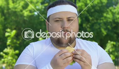 Şişman adam yeme hamburger için abur cubur, irade eksikliği bağımlısı çalışmadan sonra