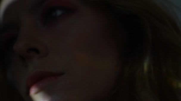 Beau visage féminin éclairé par des rayons de lumière colorés obscurité, gros plan 