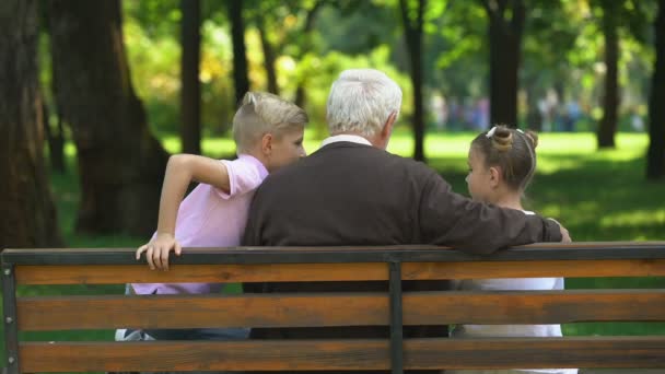 Små Barn Dela Hemligheter Med Farfar Vilar Bänken Parken Bakifrån — Stockvideo