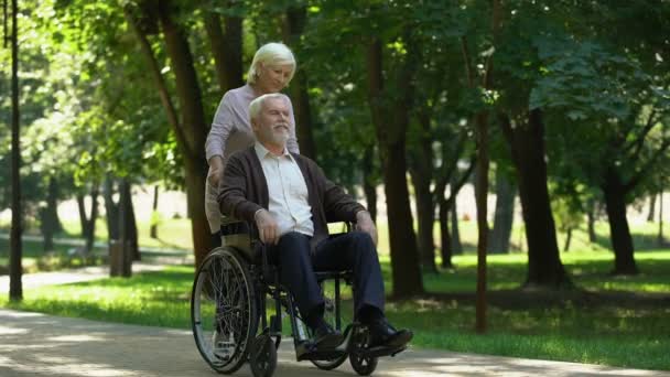 在公园散步的成年夫妇 妻子亲吻她残疾的丈夫 — 图库视频影像