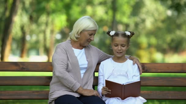 Nieta Pequeña Leyendo Libro Voz Alta Abuela Pasatiempo Parque — Vídeo de stock