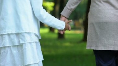 Büyükanne ve torunu elele, mutlu bir aile park boyunca yürüyüş