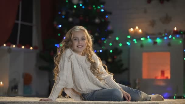 小可爱的女孩在地板上装饰的圣诞树下 微笑着对着相机 — 图库视频影像