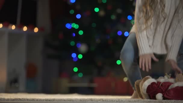 女孩把泰迪熊在地板上的圣诞老人装备 圣诞节装饰闪闪发光 — 图库视频影像