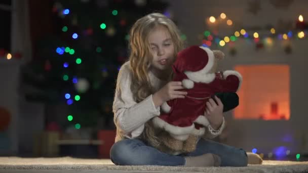 Ευτυχισμένος Κορίτσι Αγκαλιάζοντας Αρκουδάκι Santa Κοστούμι Κοντά Διακοσμημένο Δέντρο — Αρχείο Βίντεο