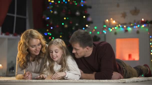 Chica Con Los Padres Pegando Sobre Para Santa Bajo Árbol — Vídeos de Stock