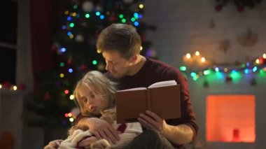 Özenli Baba Noel için dekore edilmiş ağaç yakınındaki uykulu kız masal okuma