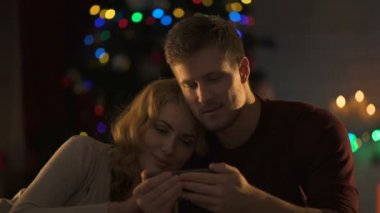 Güzel çift köpüklü X-mas ağaç, samimiyet altında smartphone film izlerken