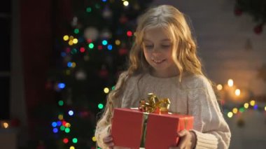 Sevimli sarışın kız uzun tutarak mevcut, sihirli bir Noel atmosfer beklenen
