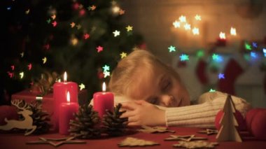 Sevimli kız masanın üzerinde uyuya Noel kutlamaları için rahat ev dekore edilmiş