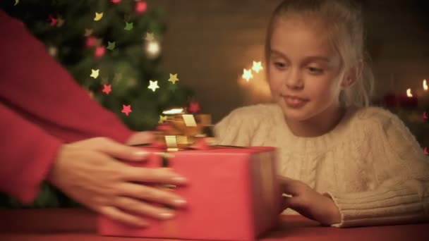 Señora que da el regalo de Navidad de la muchacha emocionada, tiempo feliz de la fiesta, árbol chispeante — Vídeos de Stock