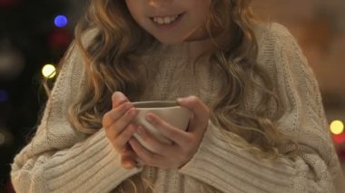 Küçük kız kış kazak fincan çay, ısınma Noel bekliyor