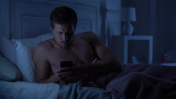 Όμορφος Αρσενικό Ξαπλωμένη Στο Κρεβάτι Επιφυλάσσει Απογοητευτικό Μήνυμα Κειμένου Smartphone — Αρχείο Βίντεο
