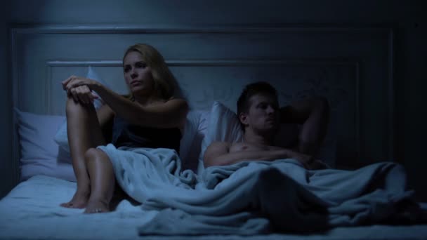 Husband and wife quarreling in bed, not looking at each other, family problems