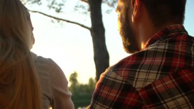 Sakallı adam ve sarılma ve riverside, arka serin günbatımı zevk kadın göster