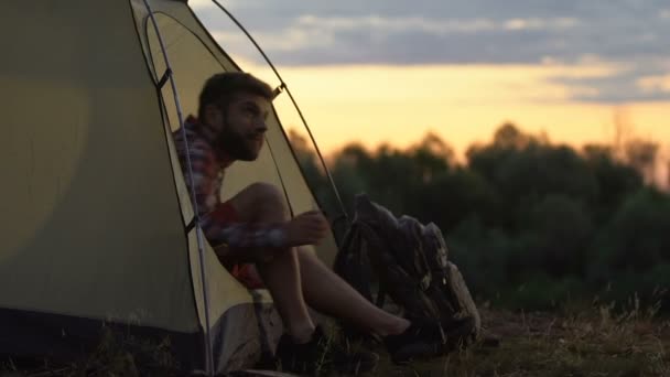 若い男のテントの中で目を覚ます 手を伸ばして あくび 休日のキャンプ — ストック動画